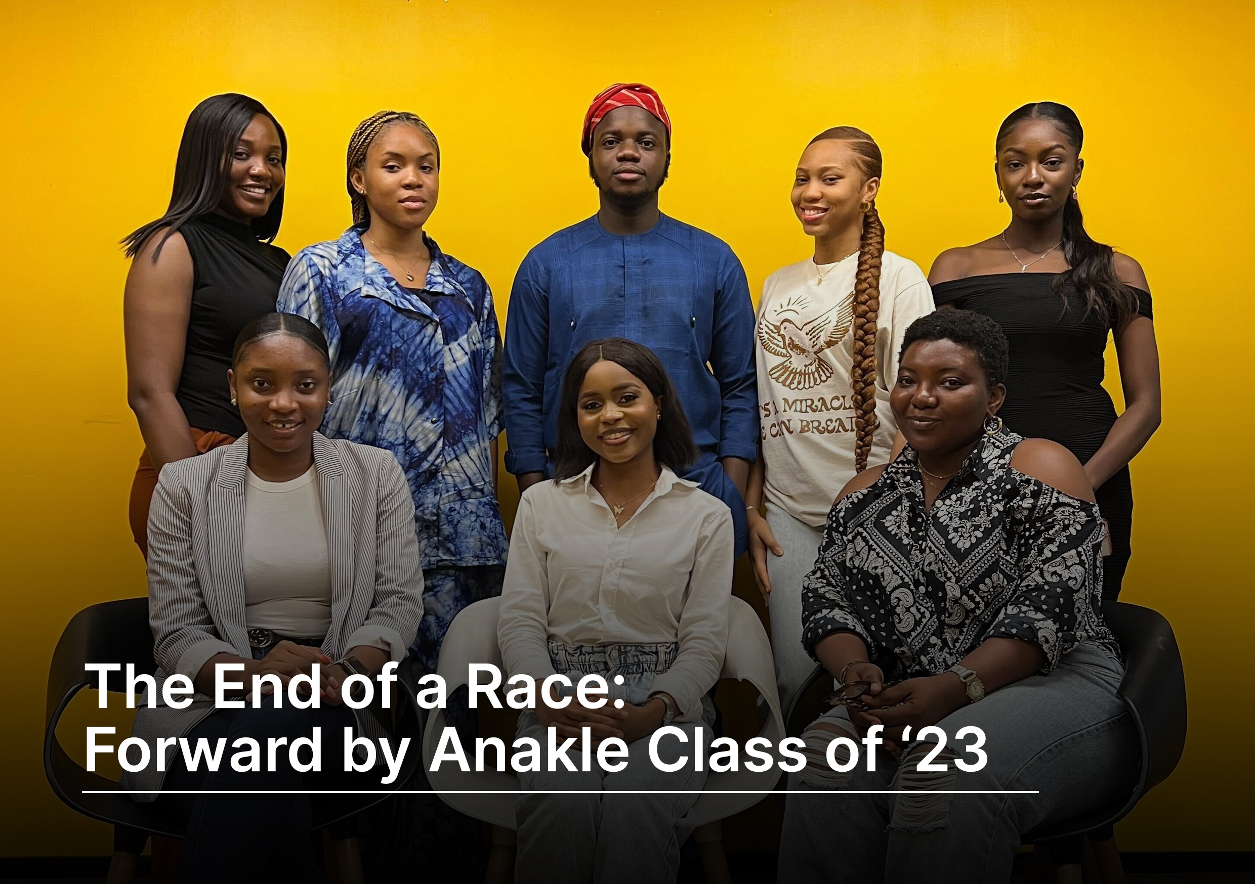 A group of 8 people (1 boy & 7 girls). 3 of the girls are sitting in front and the remaining 5 people are standing behind them with the boy at the middle of the 5.